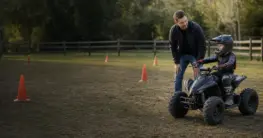 Kind übt mit gedrosseltem Kinderquad unter direkter Aufsicht